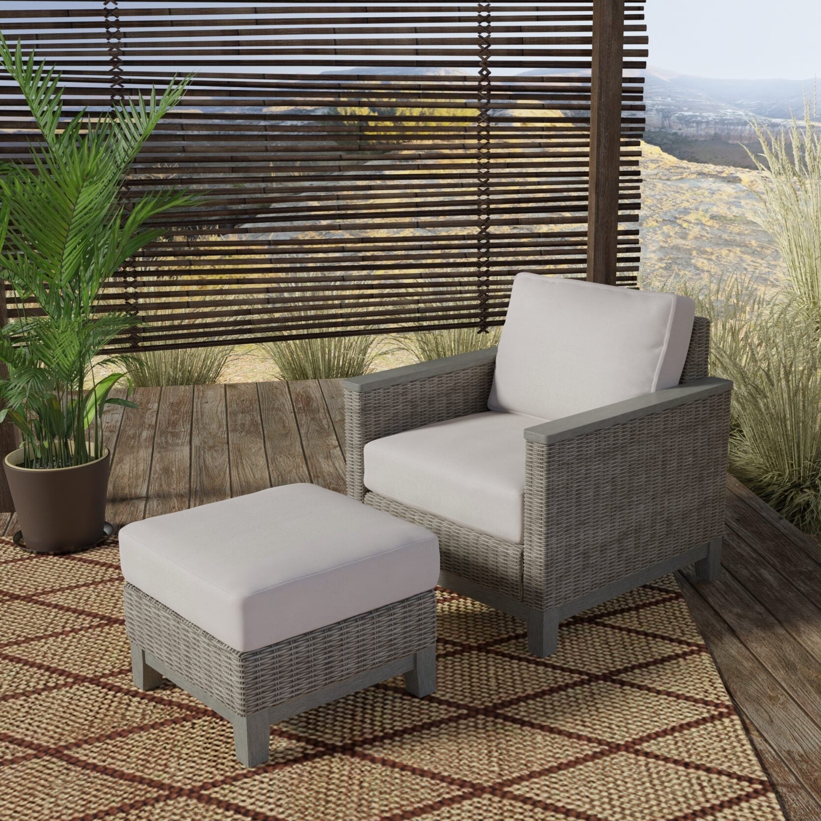 Gray wicker outdoor patio furniture set featuring a single armchair with a white cushion and a matching ottoman, placed on a woven rug on a wooden deck.