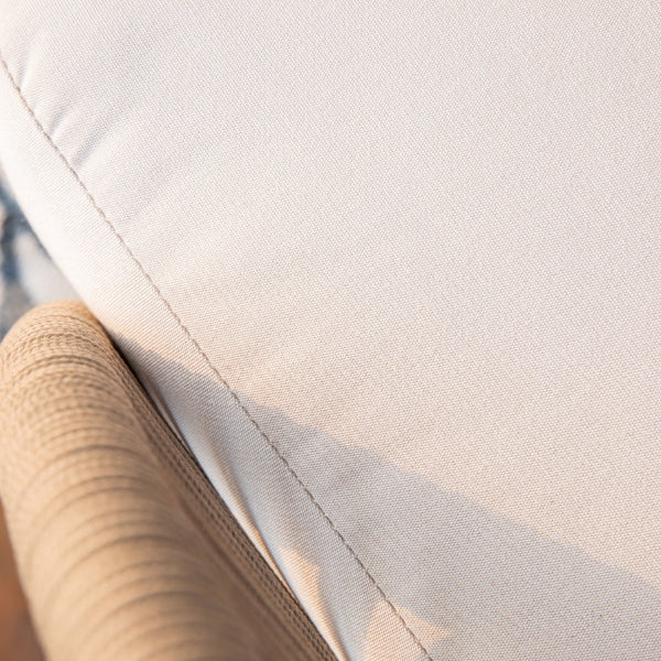Close-up detail of a light beige cushion with a ribbed beige armrest or frame edge, showing stitched seams and fabric texture.