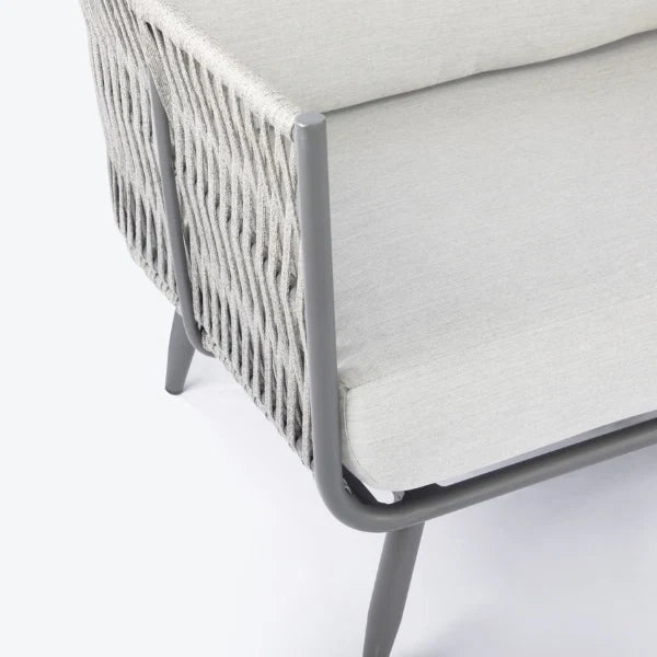 Close-up of a modern outdoor sofa corner with light gray woven rope sides, a light gray cushion, and a gray aluminum frame on a white background.