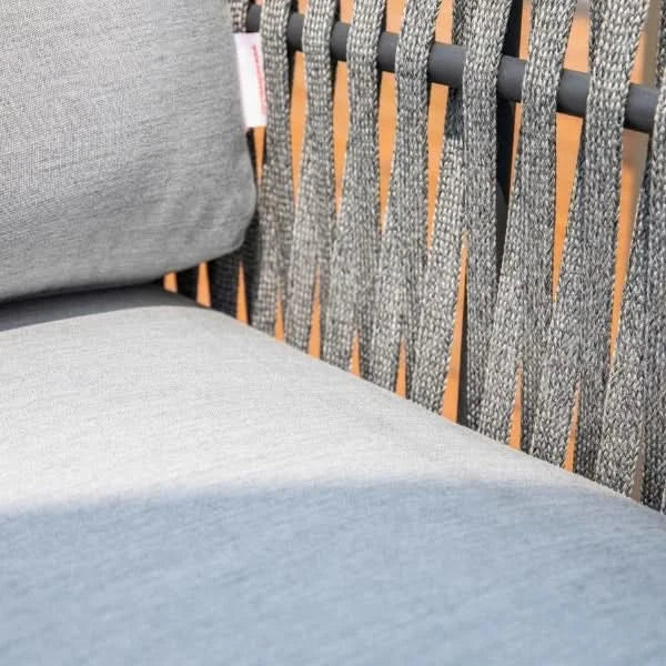 Close-up of a gray woven outdoor chair with a light gray cushion and a dark metal frame.