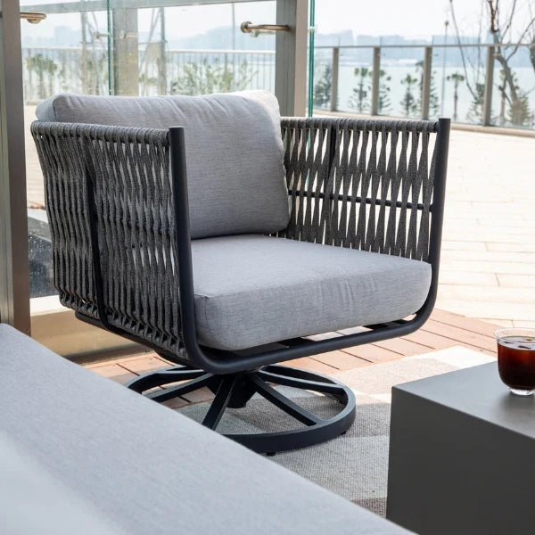 Gray cushioned chair on a patio with a view of trees and sky.