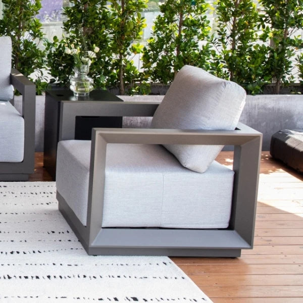 Modern outdoor lounge chair with gray frames and white cushions on a wooden deck.