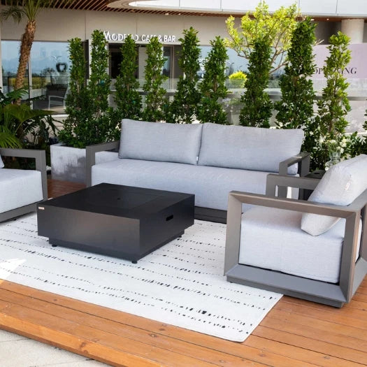 Outdoor patio set with gray sofa, chairs, and fire pit table on a wooden deck.