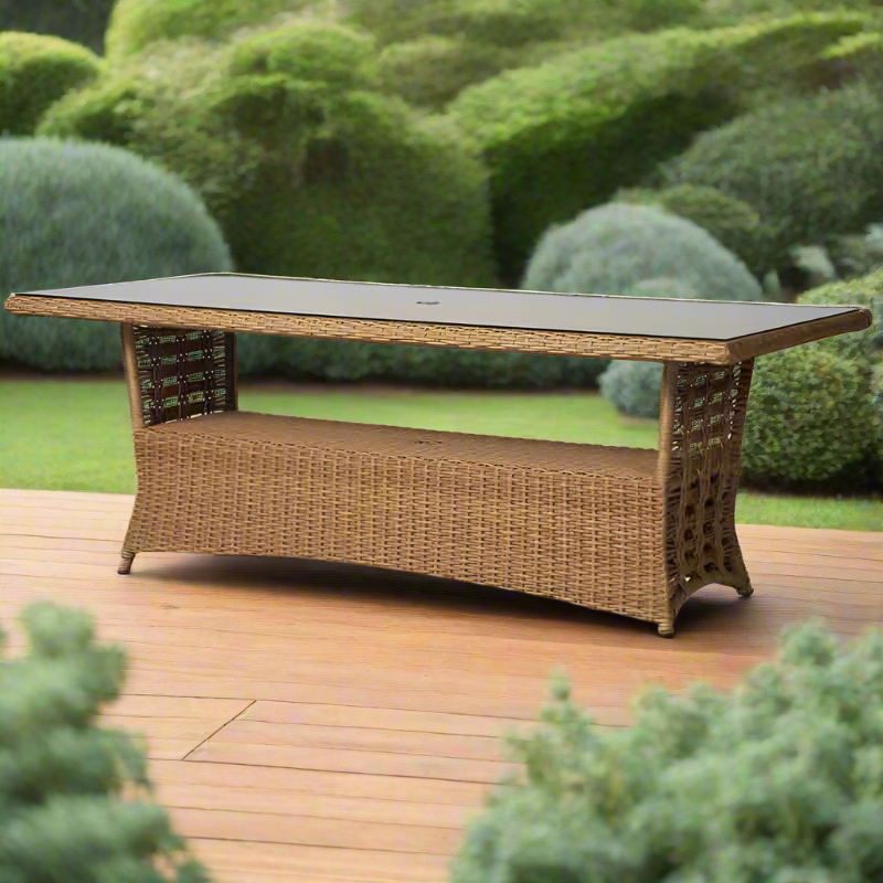Wicker outdoor table with bench on a wooden deck surrounded by greenery