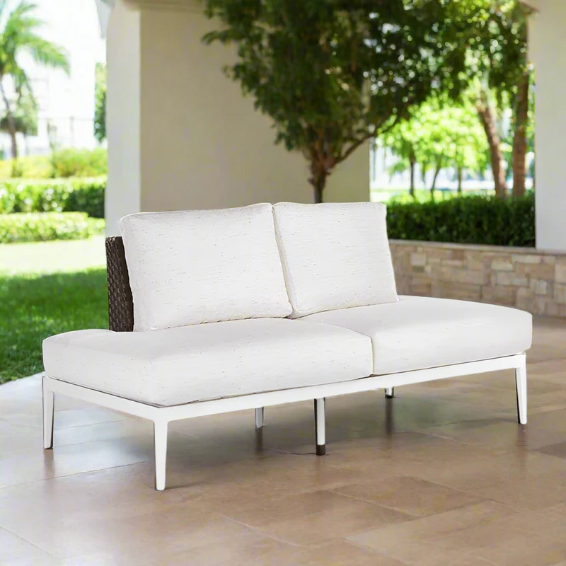 White outdoor sofa on a patio with greenery in the background