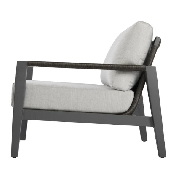 A modern outdoor lounge chair with a dark gray frame, woven armrests, and light gray cushions, shown from a side profile view on a white background.
