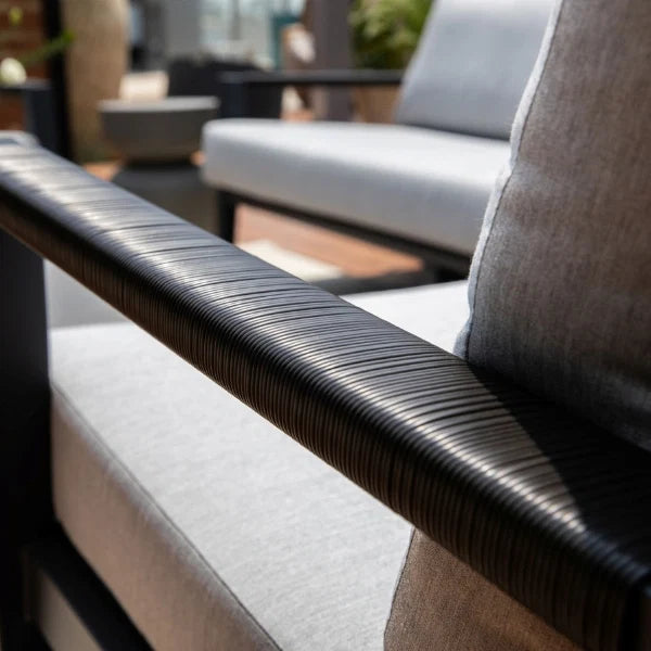 Close-up of a textured chair armrest with blurred outdoor furniture in the background