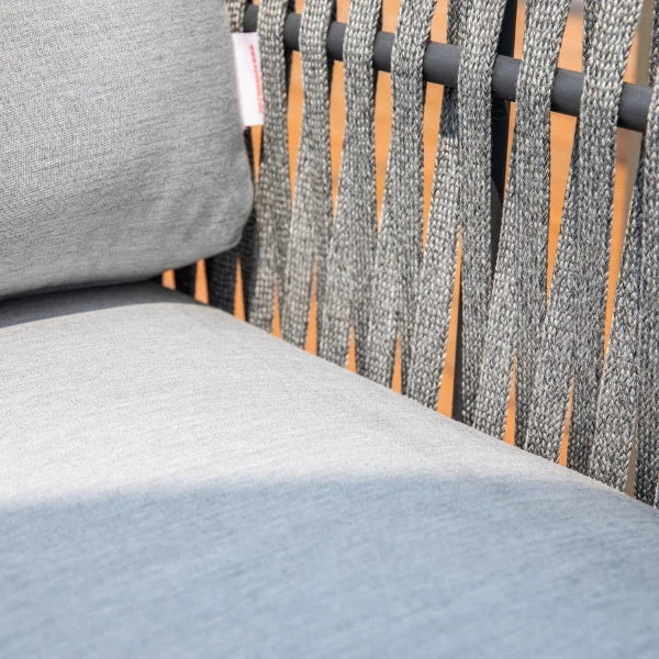 Close-up of a gray woven outdoor chair with a light gray cushion and a dark metal frame.