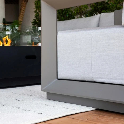 Modern outdoor sofa with a fire pit in the background