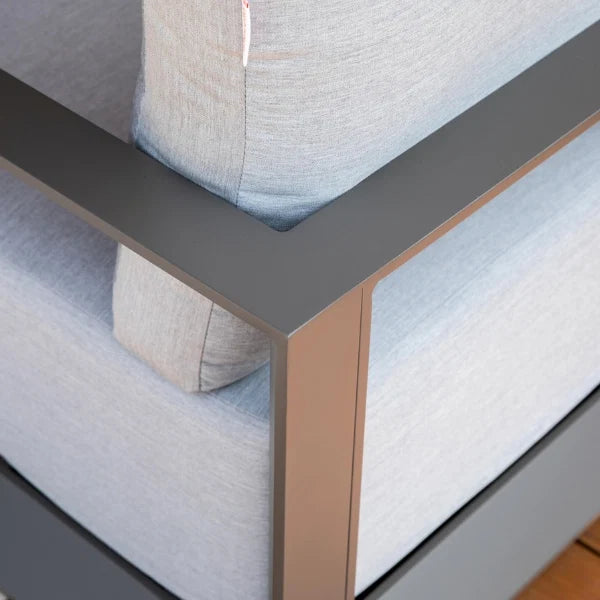 Close-up of a modern outdoor swivel chair corner with light gray textured fabric cushions and a dark gray metal frame with a rose gold accent leg.