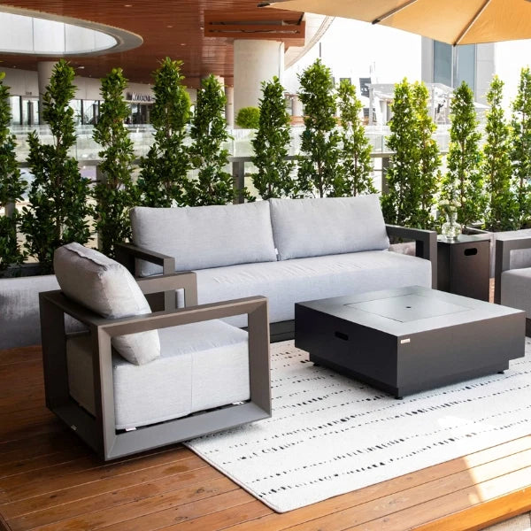 Outdoor patio furniture set with gray cushions and a fire pit table on a wooden deck.