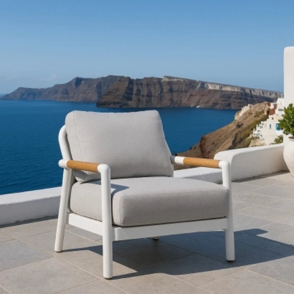 Gray chair with wooden armrests on a patio overlooking a scenic ocean view.