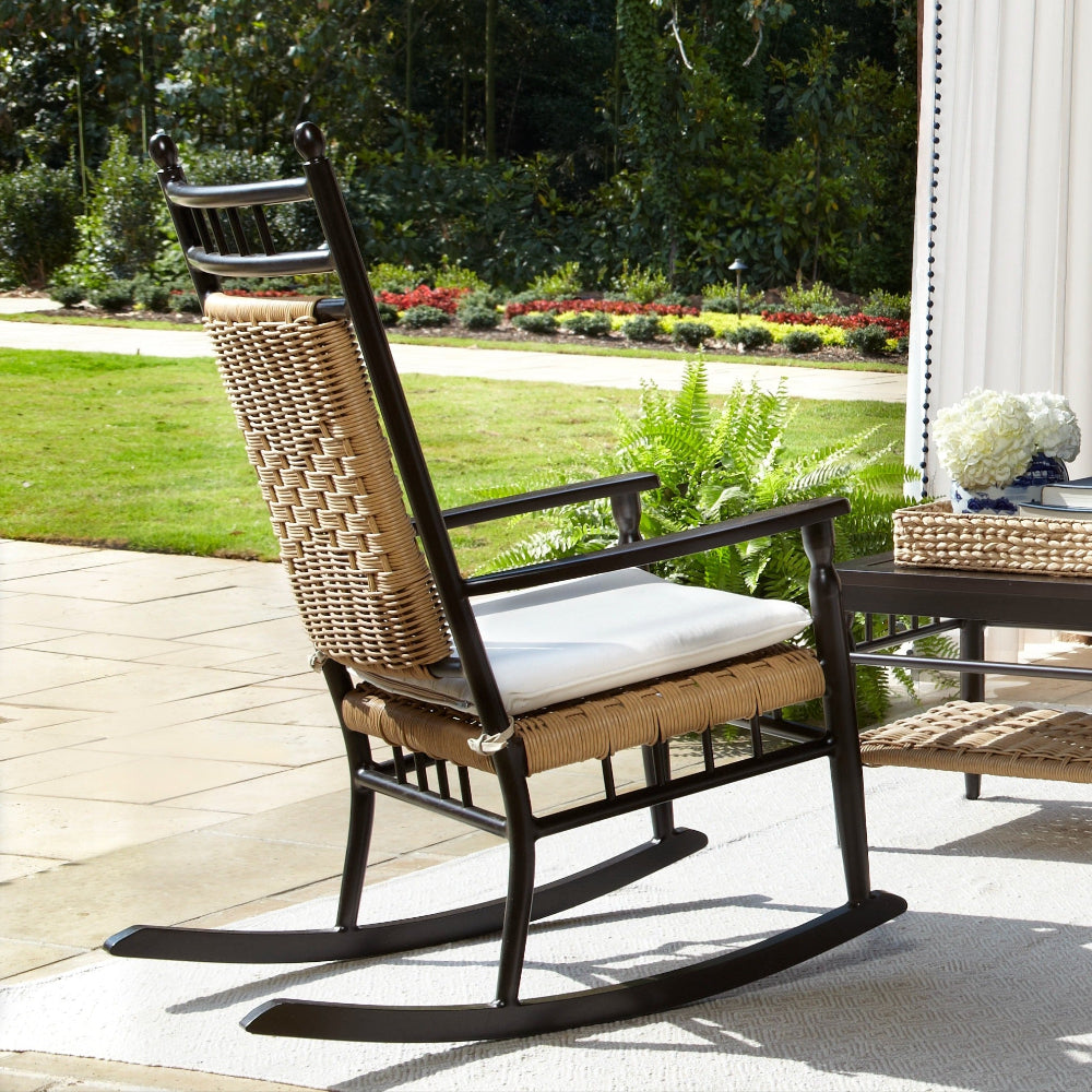 Outdoor patio set with chairs, table, and cushions on a covered patio with brick archway.